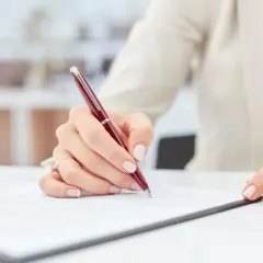 Dłoń podpisuje dokument, być może ważny weksel trasowany.