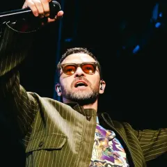 Justin Timberlake w okularach i marynarce w paski śpiewa na koncercie w Polsce.