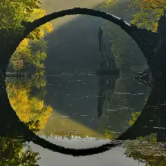 Kamienny most tworzy idealne koło z odbiciem w wodzie. Magiczny krajobraz jesienny, uchwycony przez doświadczonego **fotografa krajobrazu**.
