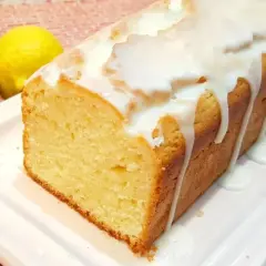 Budín de limón casero con glaseado blanco, acompañado de dos limones frescos. ¡Perfecto para la merienda!