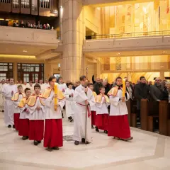 Procesja dzieci niosących świece w kościele. Dziś msza trwa dłużej, bo to uroczystość.