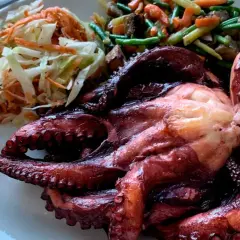 Pulpo entero asado, acompañado de ensalada de col y zanahoria, y verduras salteadas. Un festín digno de los cazadores.