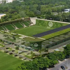 Nowoczesny stadion Warty Poznań z zielonymi dachami, panelem słonecznym i ścianą porośniętą roślinnością.