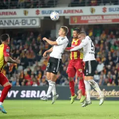 Piłkarze walczą o piłkę w powietrzu. Kibice na trybunach śledzą emocje, jakby oglądali kluczowe ekstraklasa transfery.