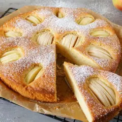 Omas weltbester Apfelkuchen, mit Puderzucker bestäubt und saftigen Apfelscheiben, wartet darauf, genossen zu werden.