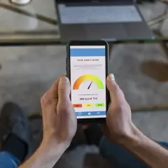 Niski wynik kredytowy? Sprawdź, co zrobić, gdy masz brak zdolności kredytowej. Telefon pokazuje wynik 506/715.