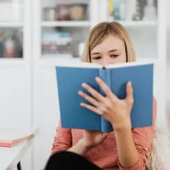 Dziewczynka pochłonięta lekturą, która wywołuje dreszczowiec. Jej oczy błyszczą, gdy śledzi kolejne zwroty akcji.
