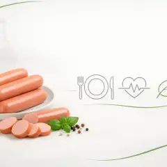 Parówki na talerzu, obok plasterki i bazylia. Ikony sugerują, czy parówki są lekkostrawne i zdrowe.