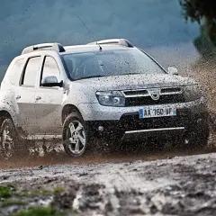 Srebrny Dacia Duster pruje przez błoto, pokazując, że to jedne z **aut tanich w utrzymaniu**, gotowe na każdą przygodę.