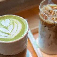 Grüner Matcha Latte mit Herz-Muster neben einem Eiskaffee. Der Matcha Mate Unterschied wird hier visuell dargestellt.