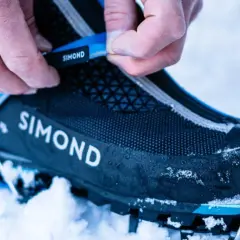 Dłonie zapinają raki do butów w śniegu. Gotowość na górską wyprawę.
