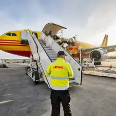 Pracownik DHL nadzoruje załadunek przesyłki lotnicze do samolotu.
