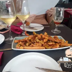 Tapas y copas de vino en el bar La Cala Almería. Un plato de patatas fritas con salchichas y una cerveza acompañan la comida.