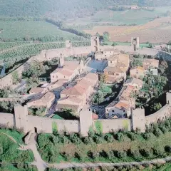 Vista aerea di Monteriggioni, un borgo medievale fortificato in Toscana, con le sue mura intatte e le torri che si stagliano sul paesaggio collinare.