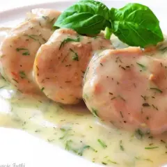 Soczyste polędwiczki w sosie koperkowym, udekorowane listkiem bazylii. Pyszne danie gotowe do podania.