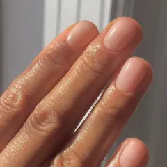Dłoń z paznokciami po japońskim manicure, w naturalnym, różowym odcieniu.
