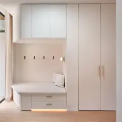 Coin salon moderne avec banquette intégrée, rangements et armoire murale. Le **pose lambris** discret souligne l'espace cosy.
