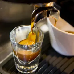 Gorący strumień kawy spływa do szklanki, tworząc idealne espresso. To właśnie taka kawa jest najlepsza!