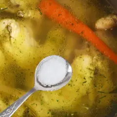 Łyżeczka soli dodawana do bulionu z kurczaka, marchewką i ziołami. Idealna porcja rosołowa.