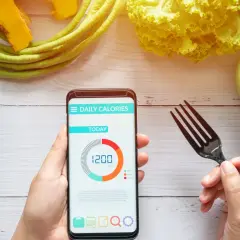 Aplikacja pokazuje dzienne zapotrzebowanie kaloryczne 1200 kcal. Obok sałatka, sok i rogalik.
