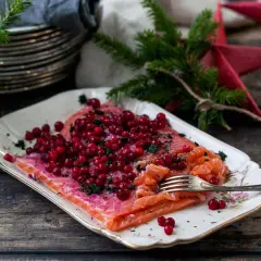 Apelsingravad lax med lingon och dill på ett vackert fat, redo för julbordet.