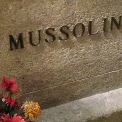 Grabstein mit der Inschrift "MUSSOLINI" und Blumen. Hier ist das Grab von Mussolini.