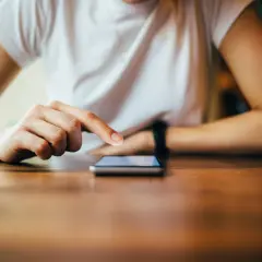 Dłoń dotyka ekranu telefonu, szukając instrukcji, jak zresetować telefon Redmi.