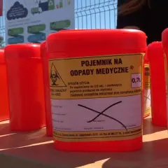 Czerwone pojemniki na odpady medyczne, w tym zużyte igły, czekają na prawidłowe wyrzucenie.