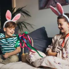 Dzieci w króliczych uszach, przygotowujące się do Śmigusa-Dyngusa. Chłopiec trzyma witkę z kolorowymi wstążkami, obok koszyk z pisankami. Idealny czas, kiedy jest przerwa świąteczna wielkanocna.