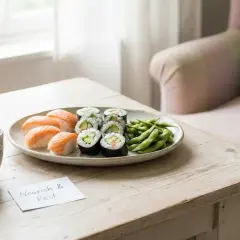En tallrik med sushi, edamame och en kopp te på ett träbord. En påminnelse om att "Nourish & Rest" kan vara perfekt för en sushi gravid.
