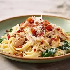 Pyszny makaron ze szpinakiem, kurczakiem i chrupiącym boczkiem, posypany parmezanem. Idealny na obiad.