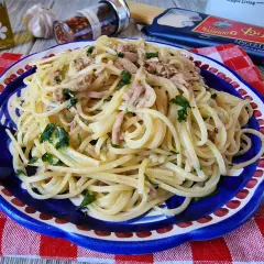 Un piatto di linguine con tonno e prezzemolo, condito con olio e peperoncino. Un classico della pasta al tonno in bianco, pronto per essere gustato.