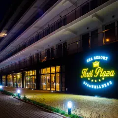 Nocny widok na nowoczesny hotel Król Plaza Spa & Wellness w Jarosławcu. Neonowy napis zachęca do sprawdzenia opinii o tym miejscu.