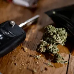 Autoschlüssel und Cannabis auf Holztisch. Ein gefährlicher Gedanke: Cannabis am Steuer.