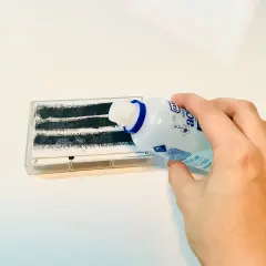 Mano versa liquido da flacone su nastro adesivo per rimuovere colla adesivi.