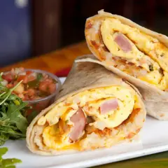 Pyszny omlet z tortillą, jajecznica, szynka i ziemniaki zawinięte w placek. Obok sałatka i salsa.