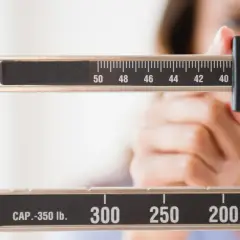 Bilancia meccanica con una mano che regola il peso. La scala mostra numeri come 50, 48, 46, 44, 42, 40, 36, 34, 32, 300, 250, 200, 150. Forse la persona sta pensando che le more fanno ingrassare.