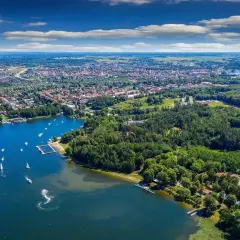 Malownicze jezioro, nad którym leży Giżycko, tętni życiem. Widać tu port jachtowy, plażę i liczne łodzie.