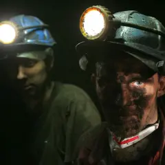 Dwóch górników w kaskach z lampami. Twarz jednego z nich jest mocno ubrudzona pyłem węglowym. Zastanawiasz się, ile zarabia górnik?