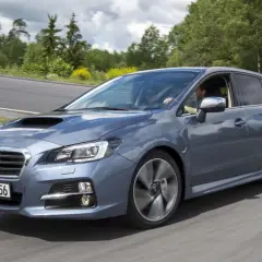 Szary Subaru Levorg na zakręcie drogi, otoczony zielenią.