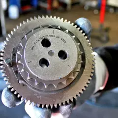 Zużyty łańcuch rozrządu objawia się wyślizganymi zębami koła. Mechanik pokazuje element z widocznymi śladami zużycia.