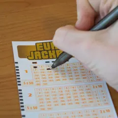 Ręka zaznacza liczby na kuponie Eurojackpot. Czy można grać w Eurojackpot mieszkając w Polsce, ale kupując los w Niemczech?