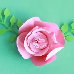 Kwiaty z papieru 3d jak zrobić? Różowa róża z zielonymi listkami, idealna do dekoracji.
