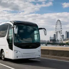 Biały autokar do Londynu jedzie w stronę miasta z Big Benem i London Eye w tle.