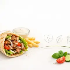 Czy kebab jest zdrowy? Na zdjęciu soczysty kebab z warzywami, frytki i sos. Obok ikony serca, liścia i sztućców.
