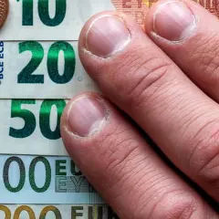 Dłonie na banknotach 10, 20, 50, 100 euro i monetach. To archiwum kursu euro.