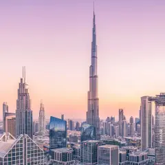 Widok panoramy Dubaju z Burdż Chalifą na pierwszym planie, w blasku zachodzącego słońca.