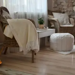 Gemütliche **hygge einrichtung**: Korbstühle, ein weicher Überwurf und ein weißer Pouf laden zum Entspannen ein.