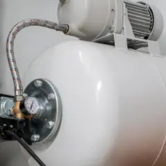 Biały zbiornik hydroforowy z manometrem i wężem. Może to oznaczać, że hydrofor często się włącza.