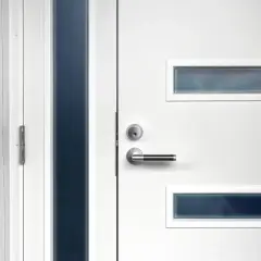 Nowoczesne białe drzwi wejściowe z metalową klamką i wąskimi, ciemnymi przeszkleniami. Dowiedz się, jak zmierzyć drzwi wejściowe.